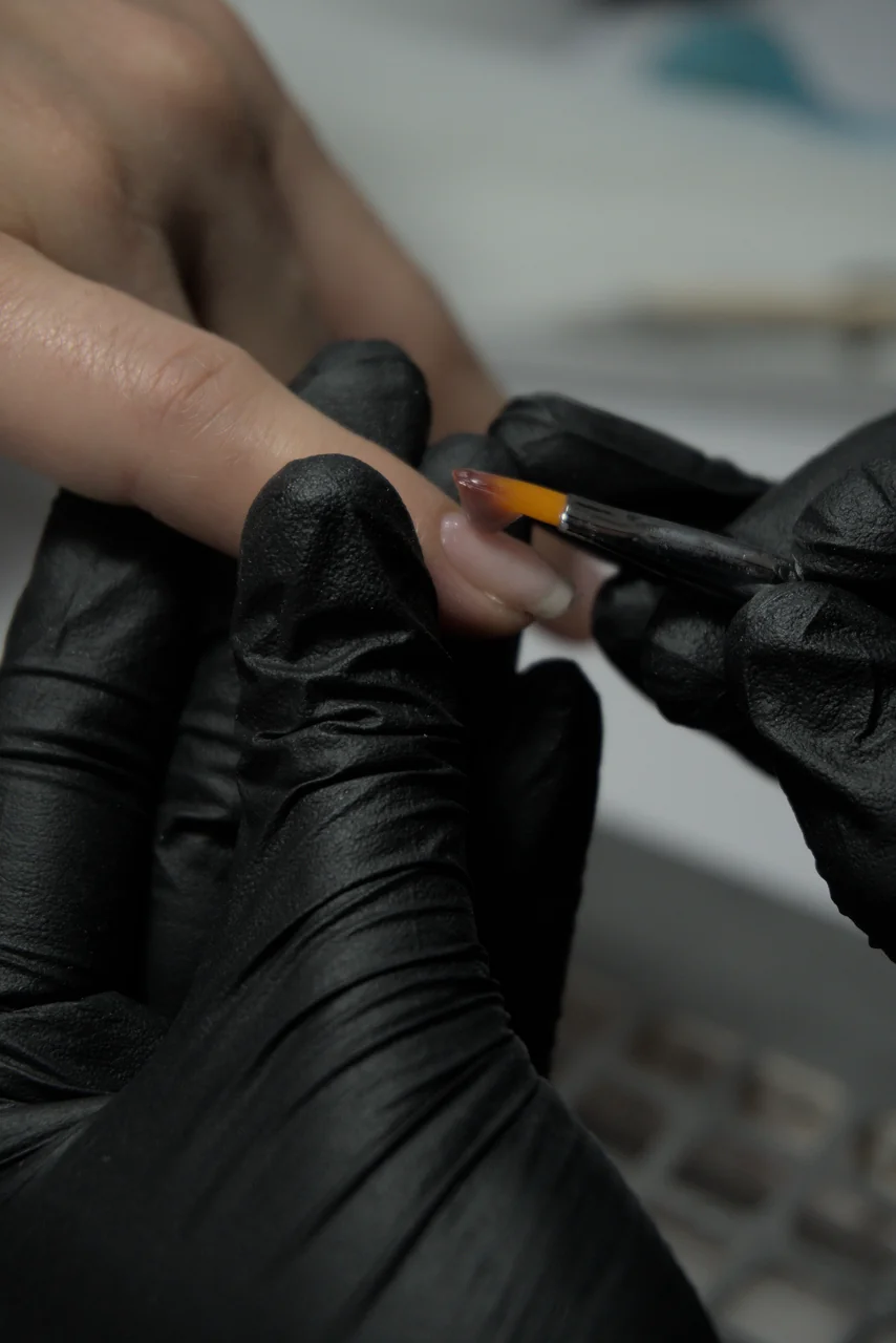 Nail technician applying delicate polish and structure with precision